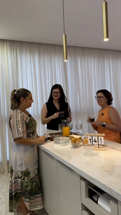 Moradora e profissionais reunidas ao redor de uma bancada de pedra em um apartamento