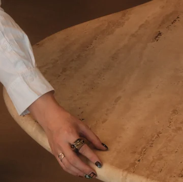Detalhe da borda orgânica em travertino da Mesa Onda